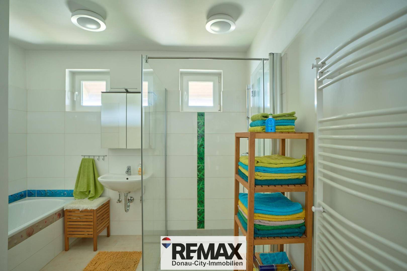 Modernes Badezimmer mit Dusche, Badewanne und beheiztem Handtuchhalter.