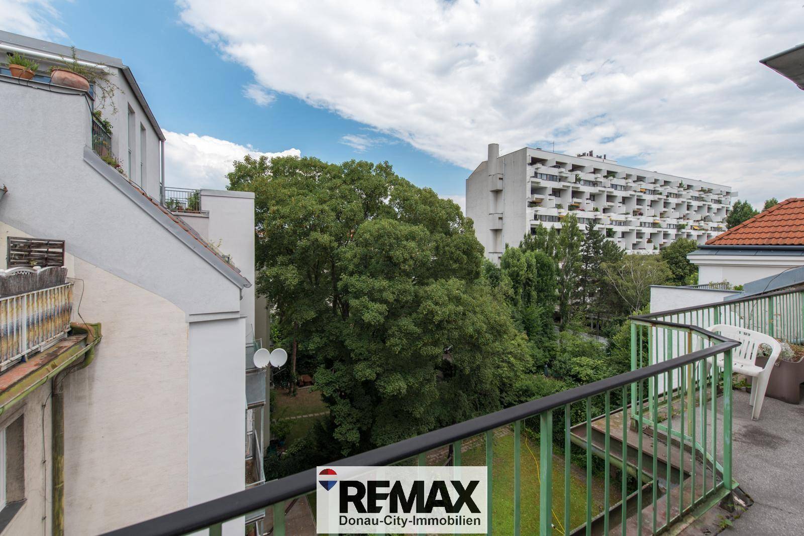 Balkon mit Blick auf grüne Bäume und umliegende Wohngebäude.