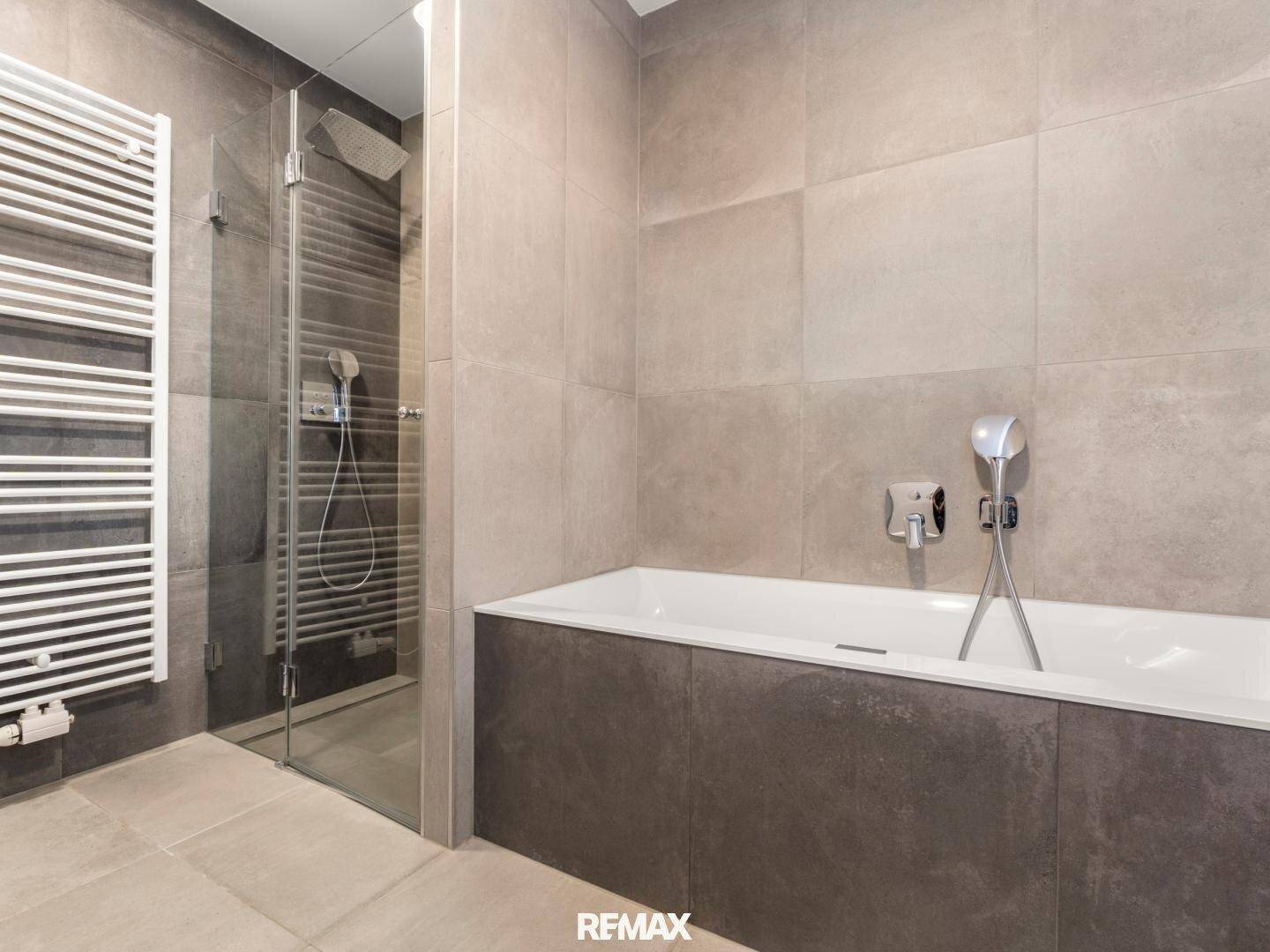 Elegantes Badezimmer mit Badewanne, begehbarer Dusche und beheiztem Handtuchhalter.