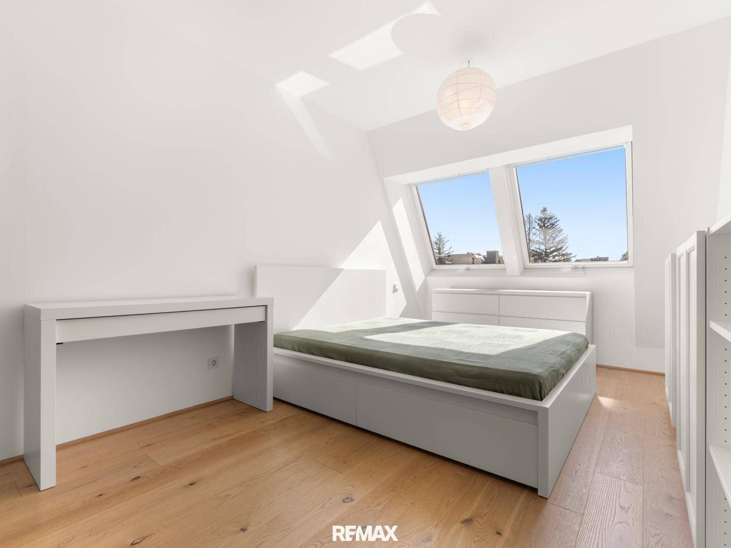 Helles Schlafzimmer mit Holzboden, Dachfenstern und minimalistischer Einrichtung.