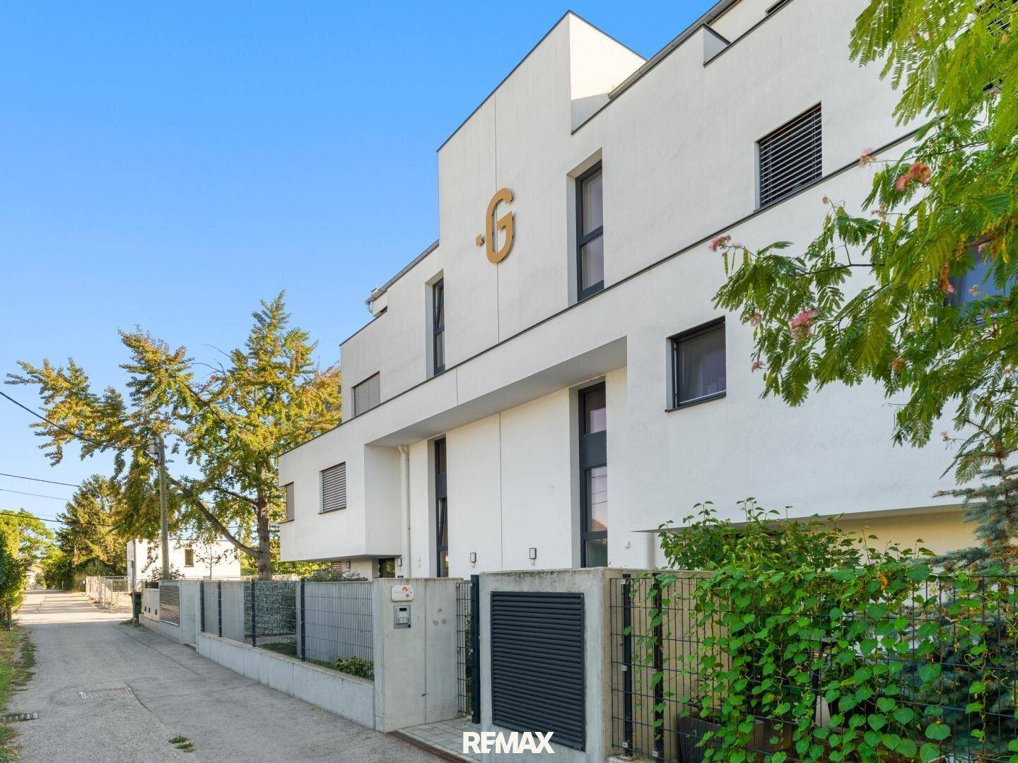 Moderne weiße Fassade eines Wohngebäudes mit klaren Linien und großen Fenstern.