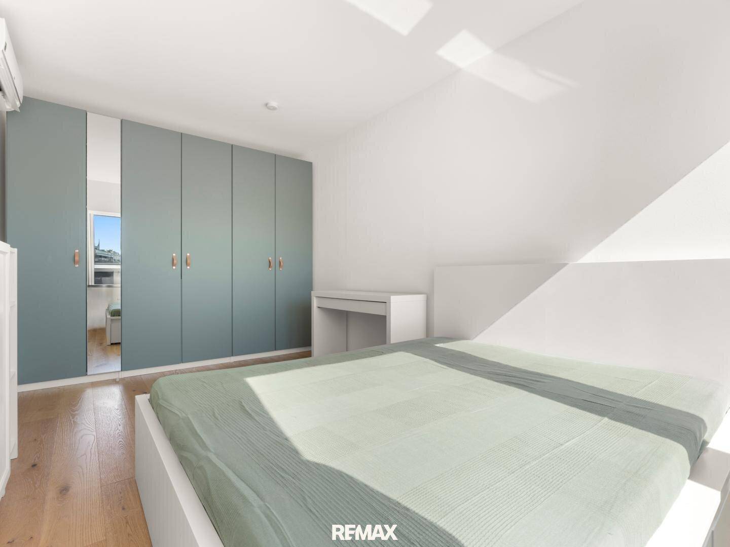 Schlafzimmer mit integrierten Kleiderschränken in Pastellfarbe und Holzboden.