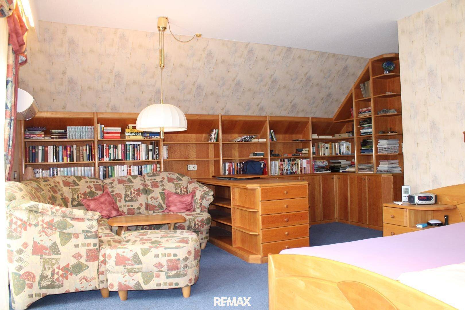 Geräumiges Schlafzimmer mit Teppichboden, Bücherregalen und einem Schreibtischbereich.
