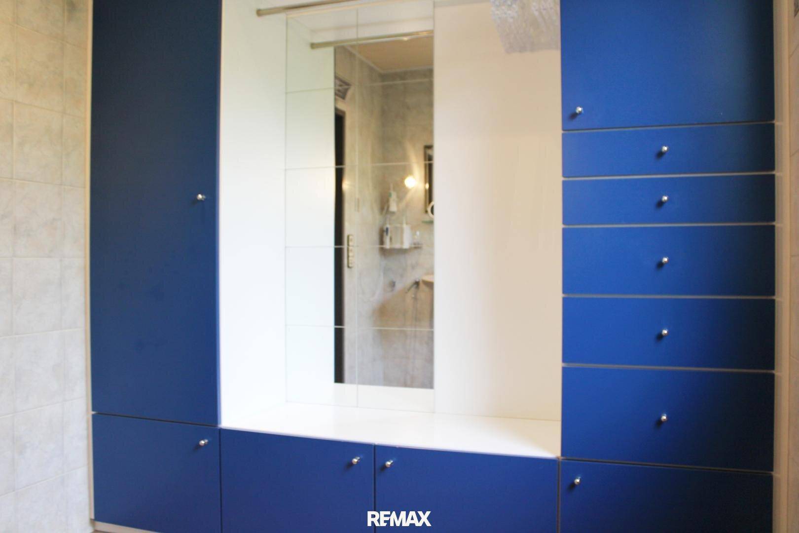 Einbauschrank mit blauen Fronten und einem integrierten Spiegel, bietet viel Stauraum.