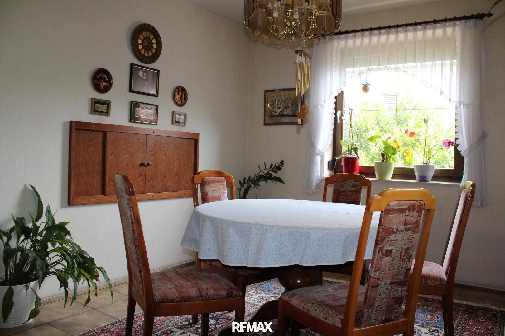 Essbereich mit traditionellem Holztisch und Stühlen, umgeben von Pflanzen und dekorativen Elementen.