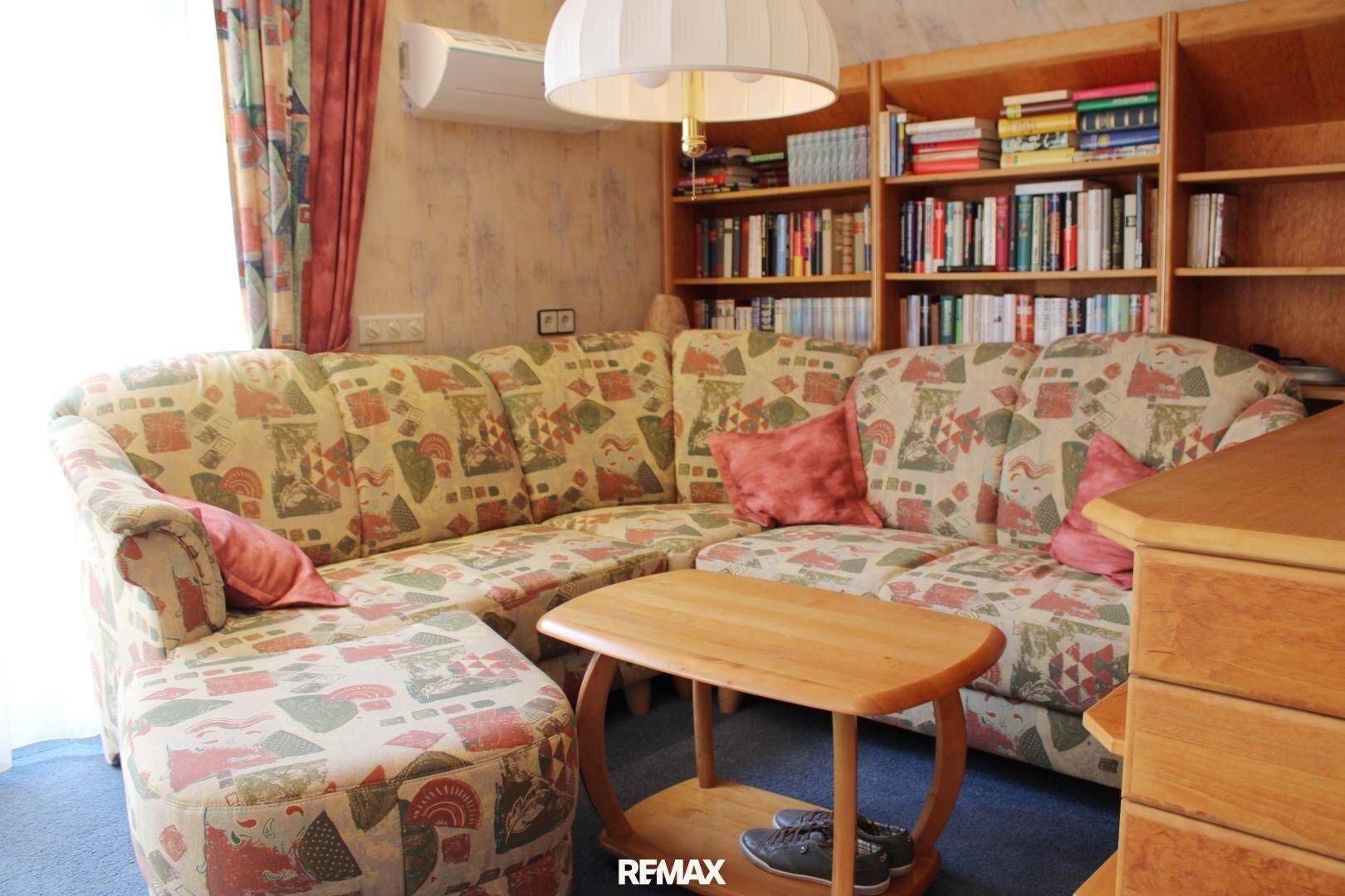 Gemütlicher Sitzbereich im Schlafzimmer mit gemustertem Sofa, Couchtisch und Bücherregal.