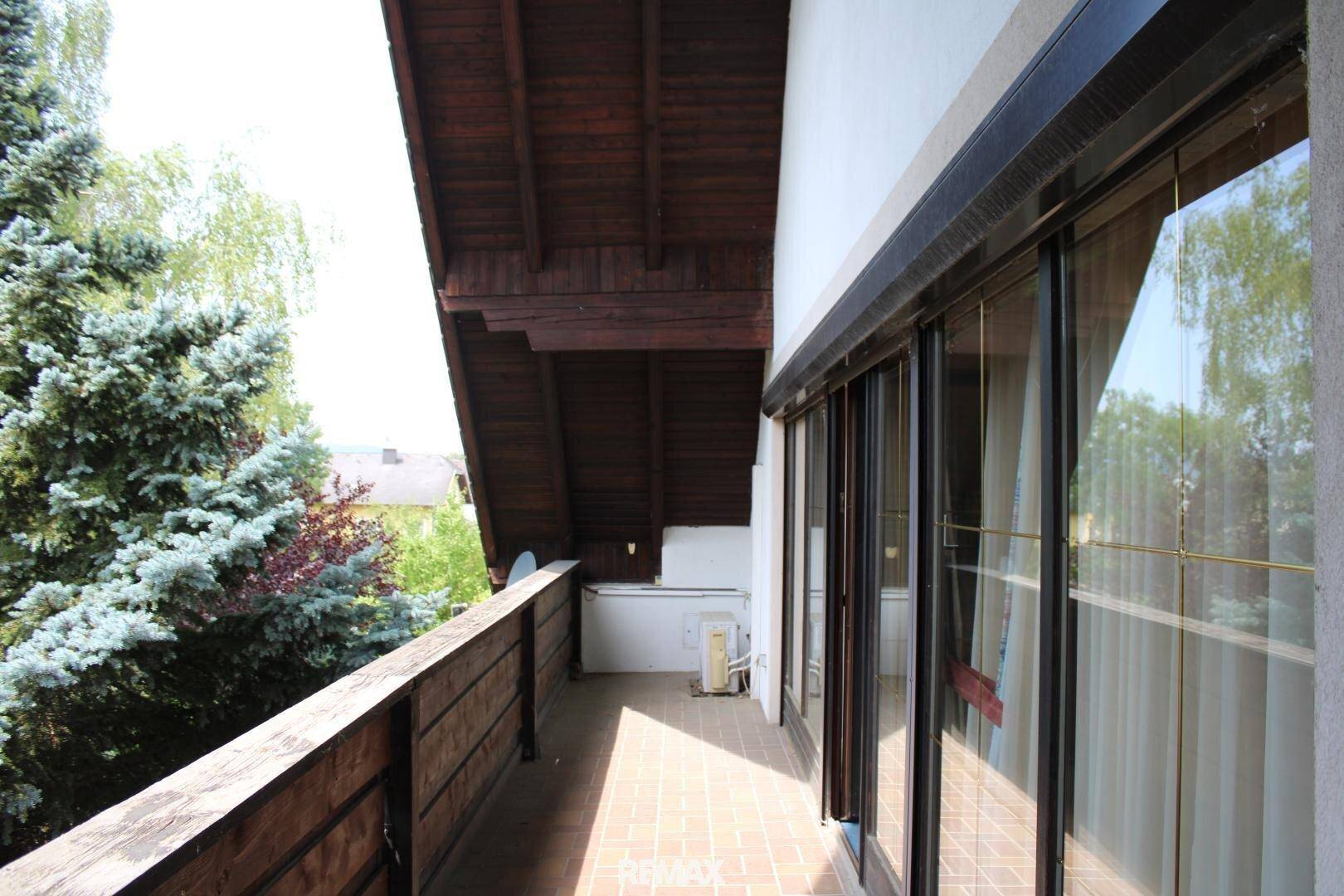 Langer Balkon mit Holzboden und Geländer, bietet einen schönen Blick ins Grüne.