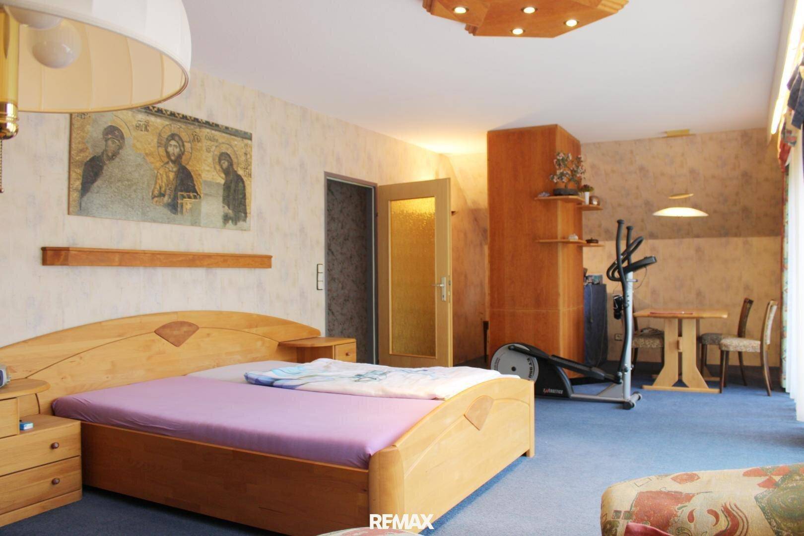Schlafzimmer mit Doppelbett, Teppichboden und einem Crosstrainer für sportliche Aktivitäten.