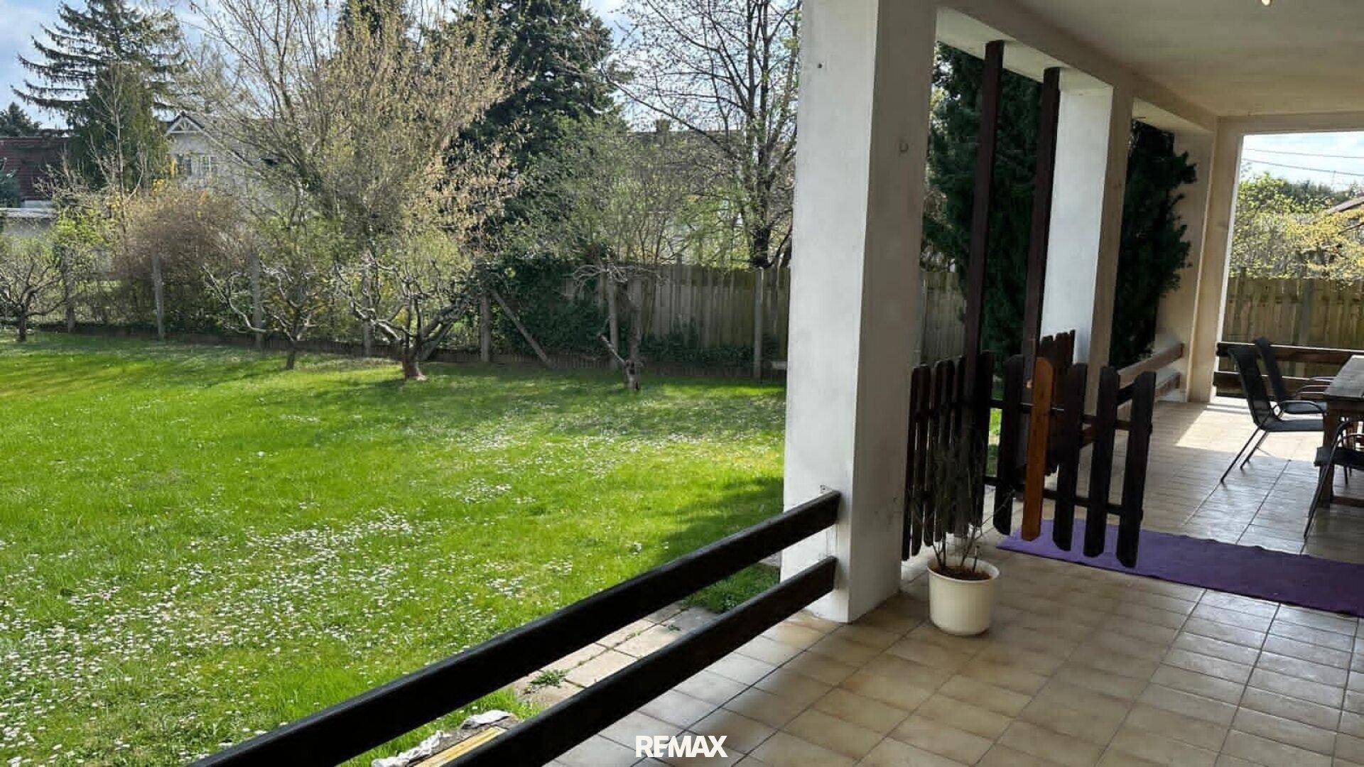 Überdachte Terrasse mit Blick auf den weitläufigen Garten und die umliegende Natur.