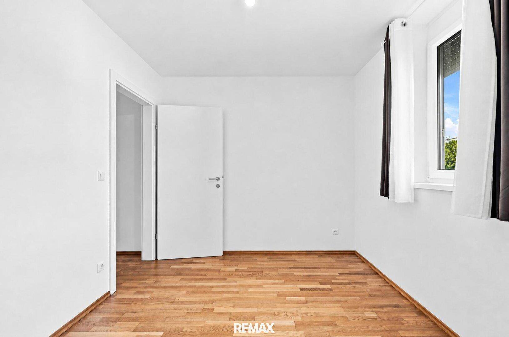 Geräumiges, helles Zimmer mit Holzboden und Fenster, bereit zur individuellen Gestaltung.
