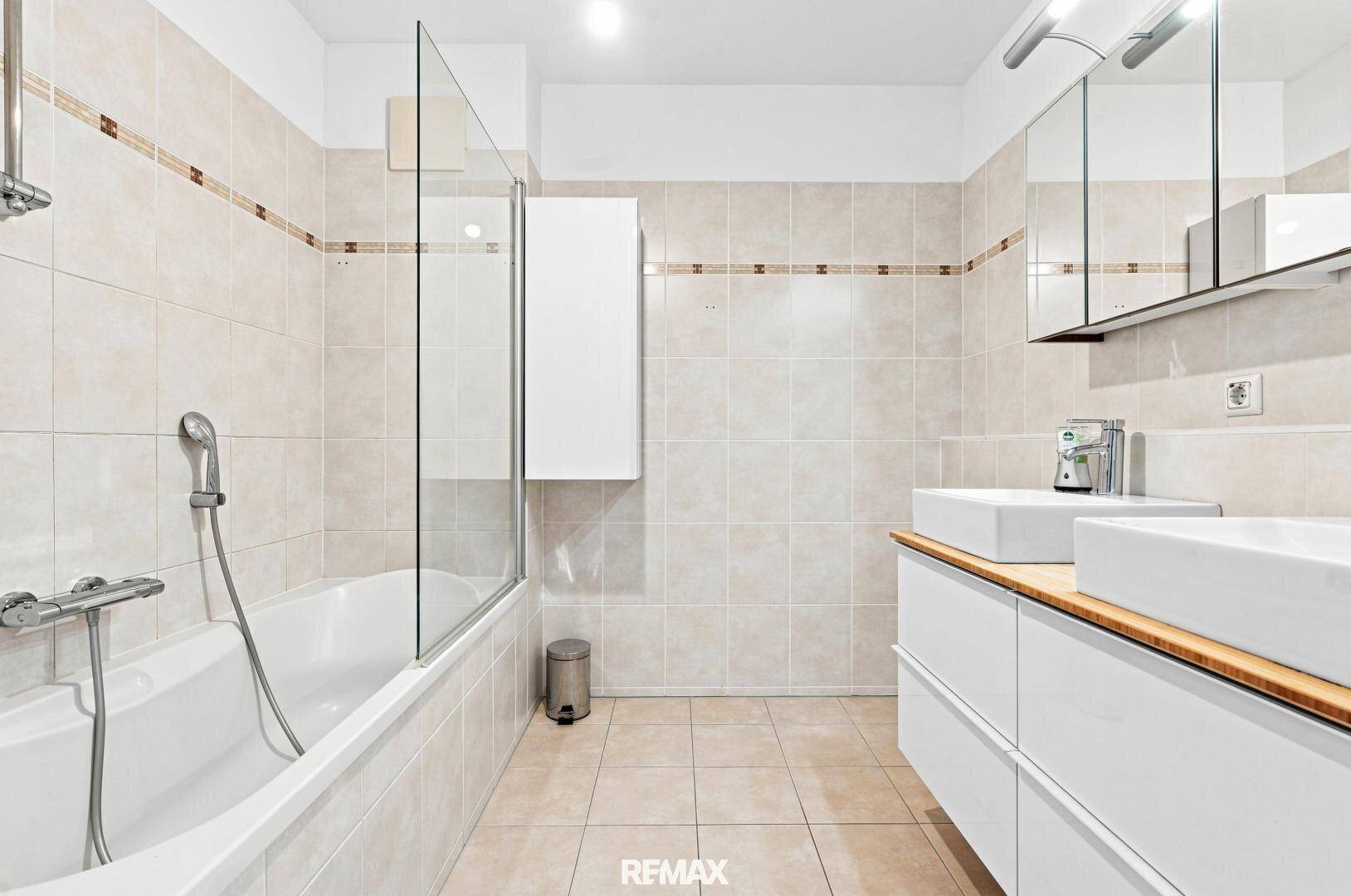 Geräumiges Badezimmer mit Badewanne, Doppelwaschbecken und Spiegelschrank.
