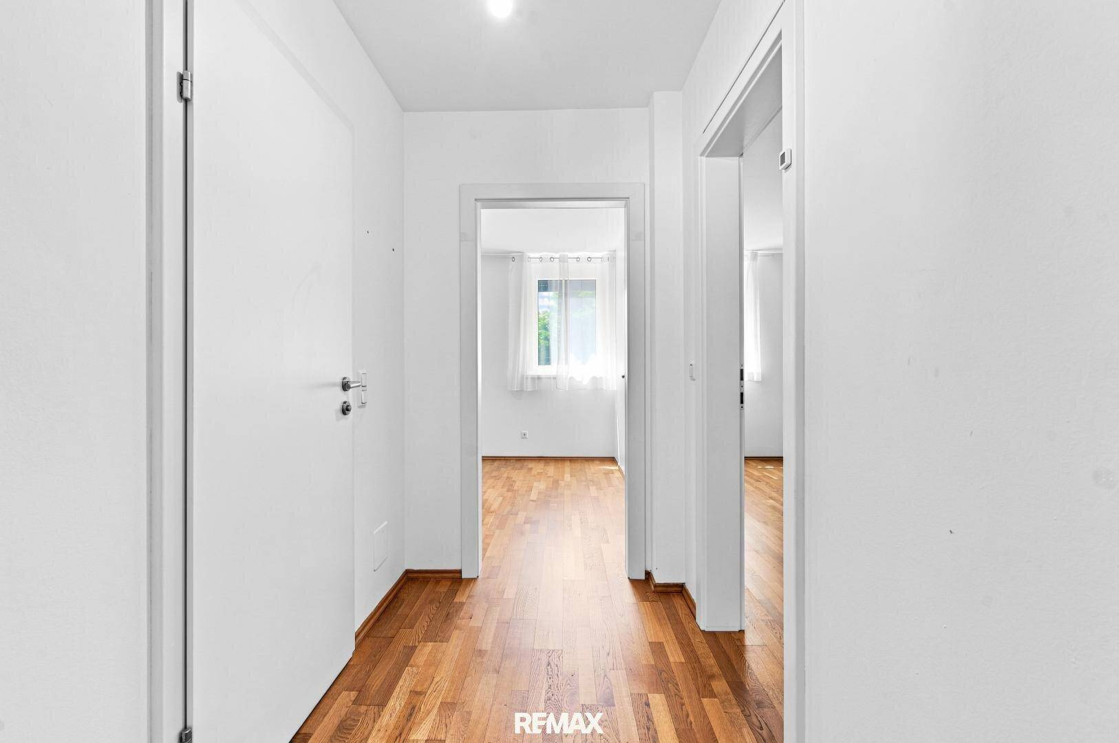 Heller Flur mit Holzboden, der zu den verschiedenen Zimmern der Wohnung führt.