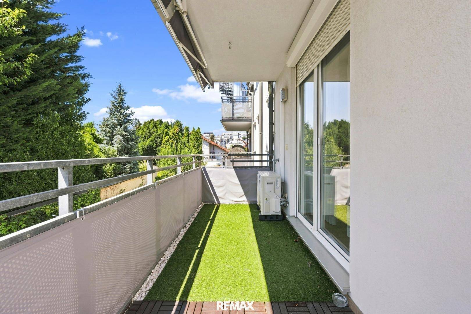 Langer Balkon mit Kunstrasen und Holzdielen, bietet einen schönen Ausblick ins Grüne.