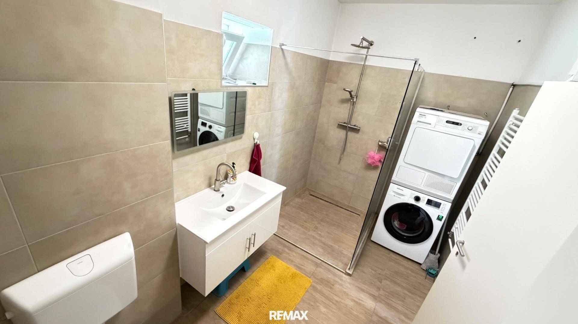 Helles Badezimmer mit Dusche, Waschbecken, Toilette und Dachfenster für natürliches Licht.