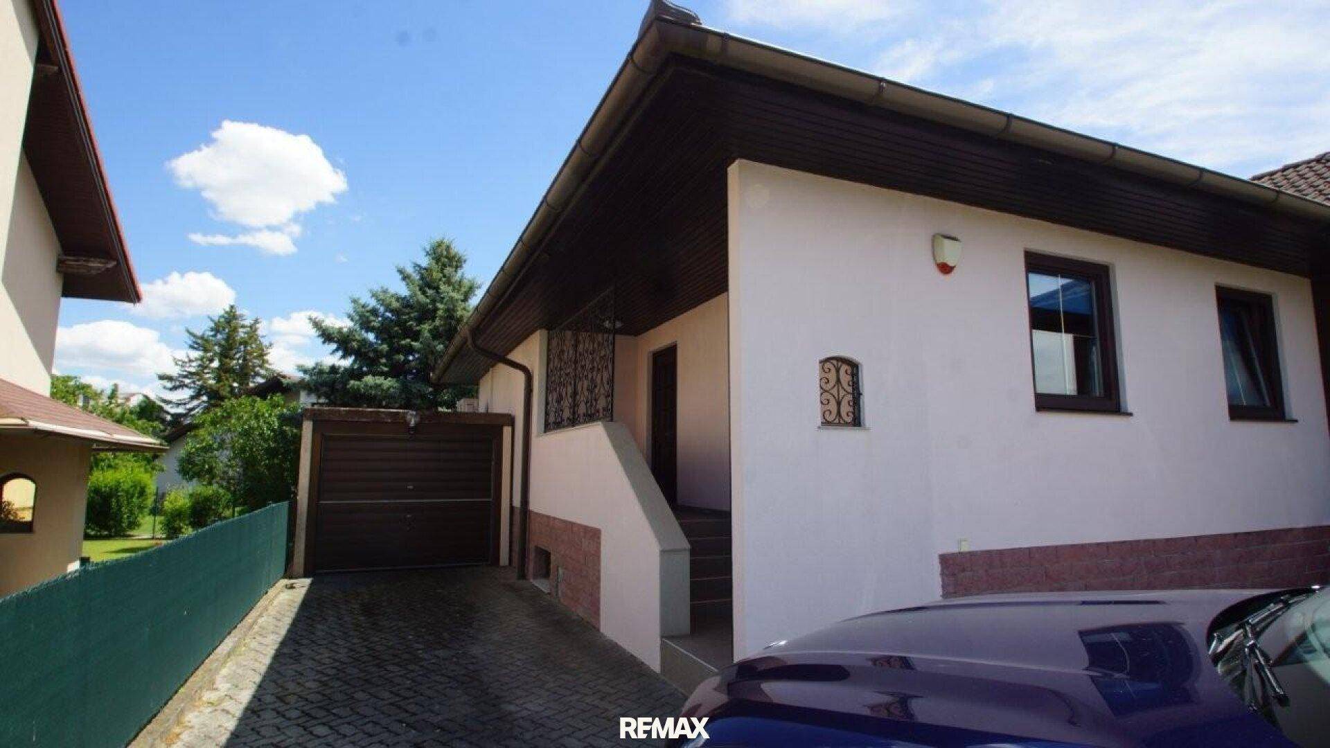 Hausfassade mit Einfahrt, Garage und Außentreppe zum Haupteingang.