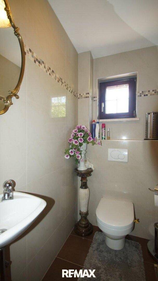 Kleines Gäste-WC mit Wand-WC, Waschbecken und einem kleinen Fenster.