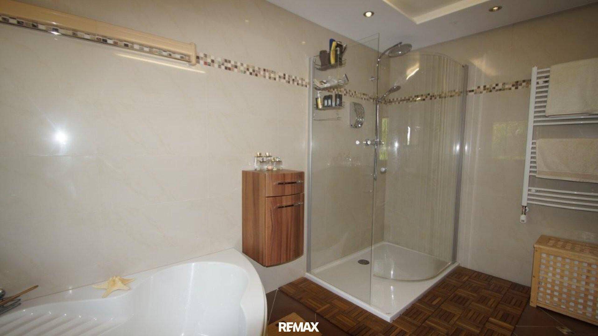 Badezimmer mit Duschkabine, Badewanne und beheiztem Handtuchhalter.