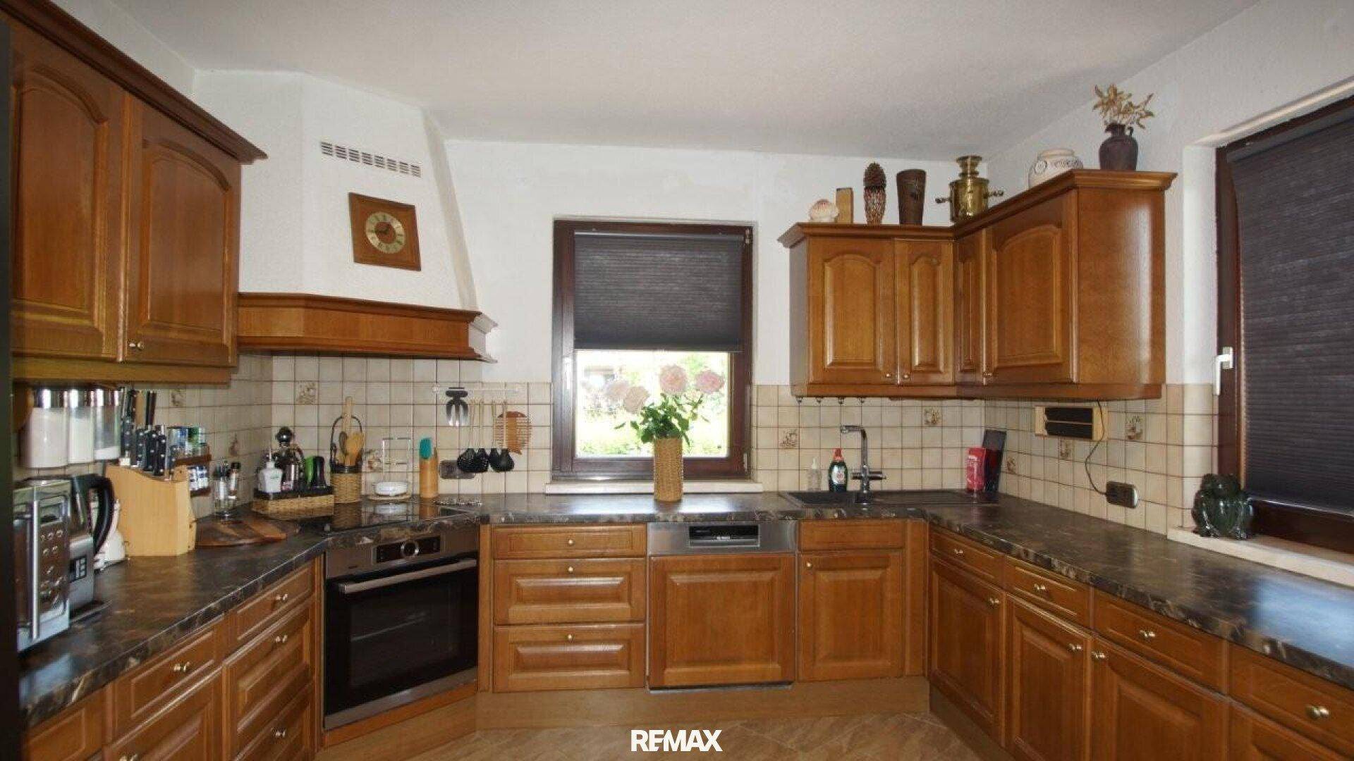 Traditionelle Holzküche mit dunkler Arbeitsplatte, integriertem Backofen und Fenster über der Spüle.
