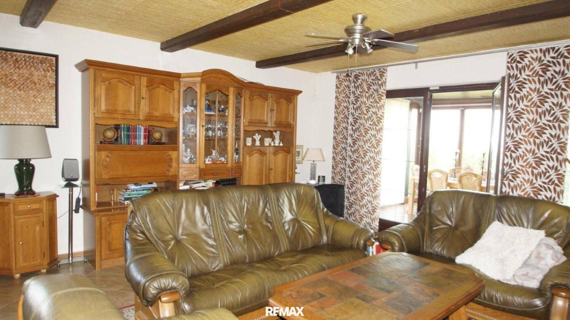Traditionelles Wohnzimmer mit Holzschrankwand, Deckenbalken und Zugang zum Außenbereich.