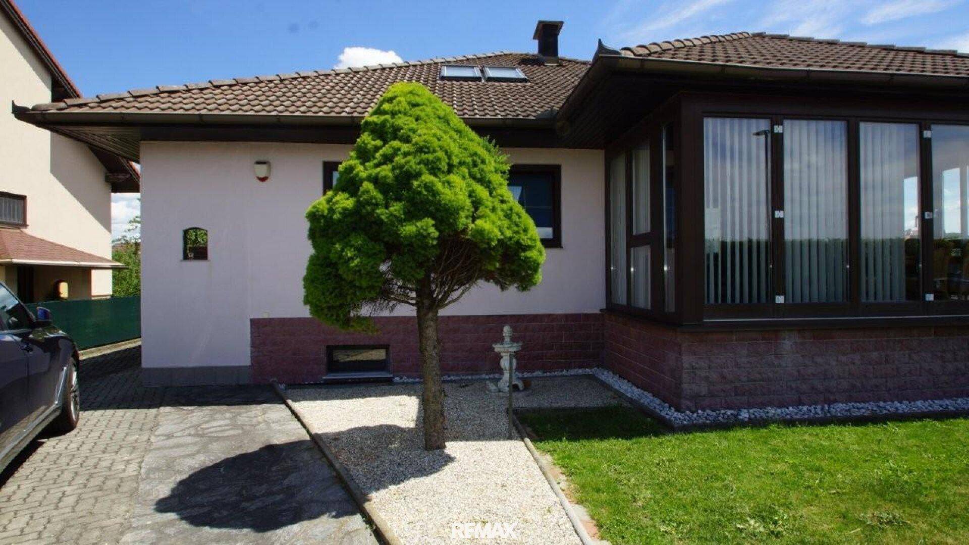 Außenansicht des Hauses mit gepflegtem Vorgarten, Kiesweg und einem kleinen Baum.