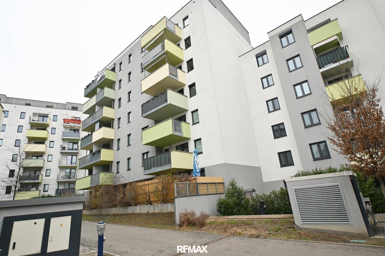 Ansicht eines modernen Mehrfamilienhauses mit Balkonen und gepflegter Außenanlage.