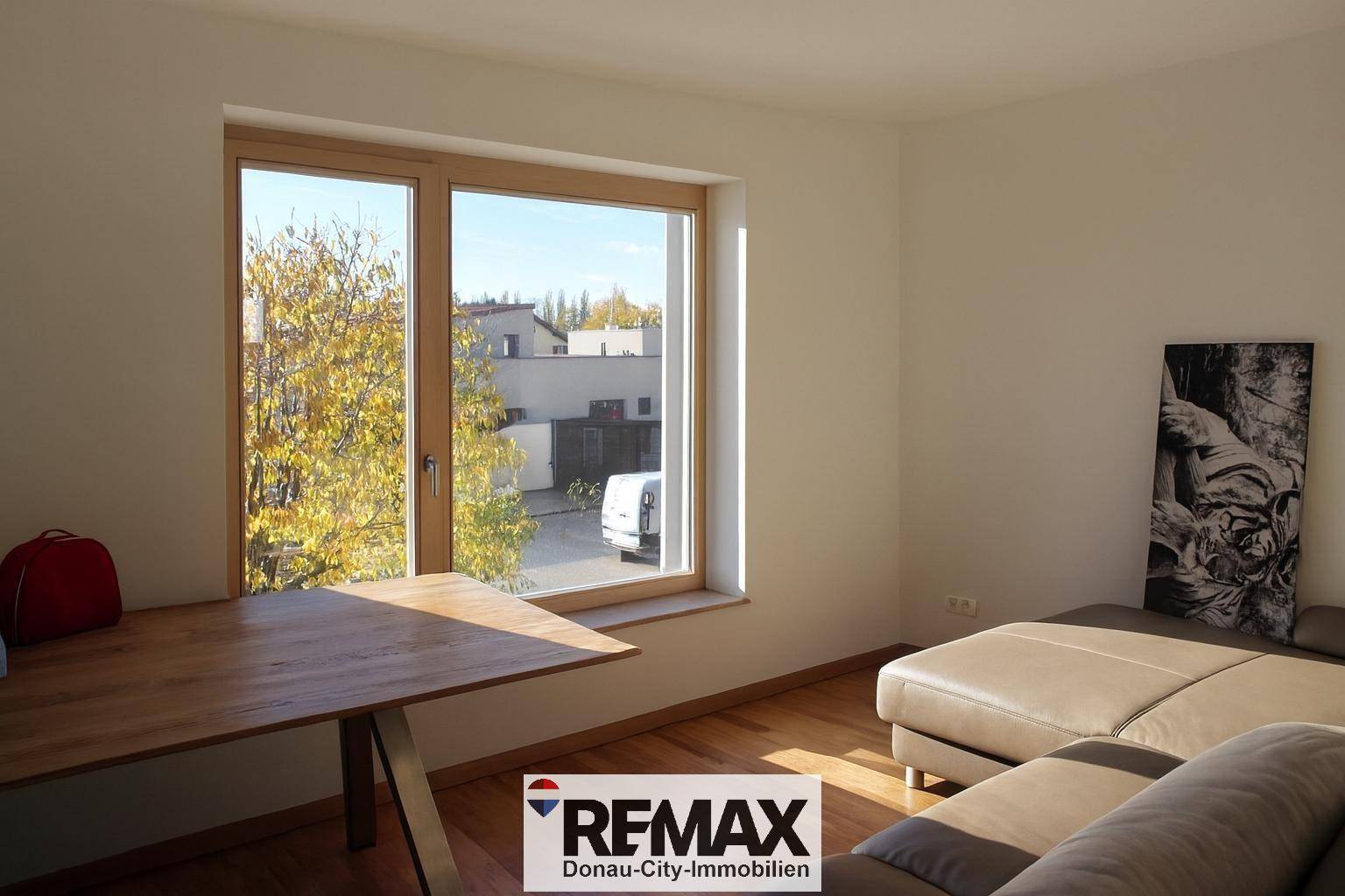 Helles Arbeitszimmer mit großem Fenster, Holzboden und Blick ins Grüne.