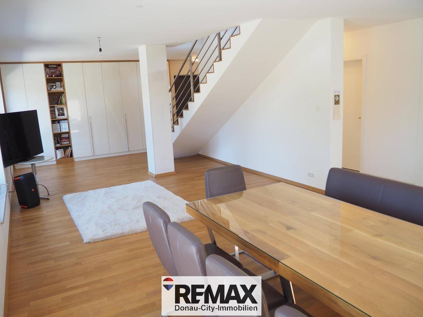Helles Wohnzimmer mit Holzboden, Einbauschränken und einer modernen Treppe.