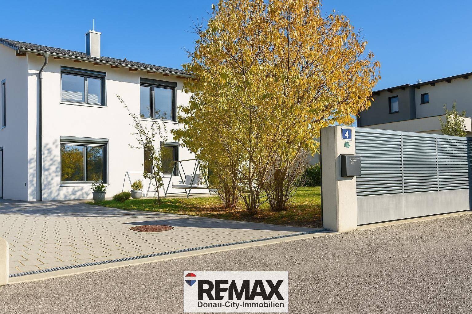 Vorderansicht des modernen Hauses mit gepflasterter Einfahrt und einem großen Tor.