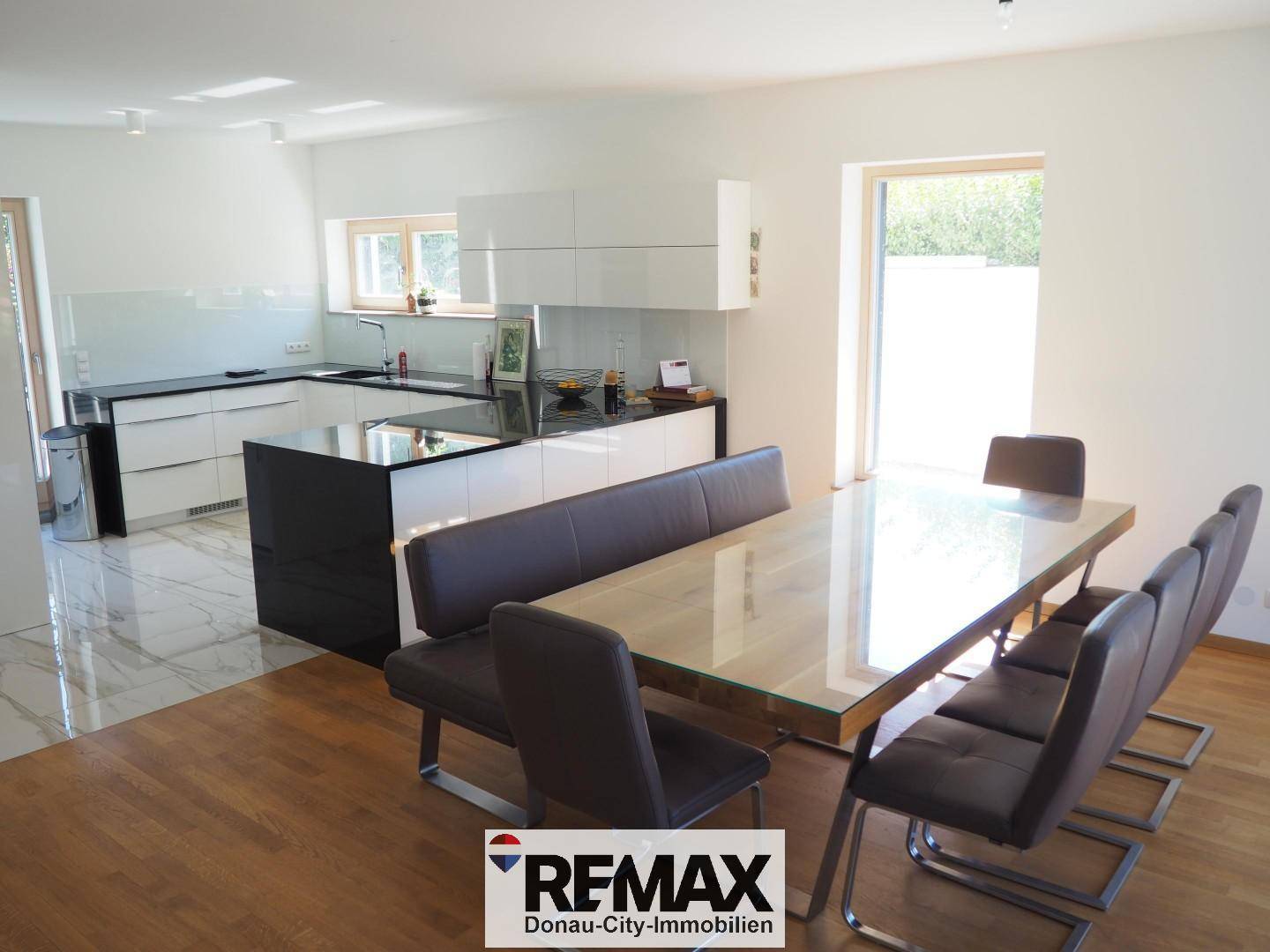 Offener Wohn-Essbereich mit moderner Küche, großem Esstisch und Holzboden.