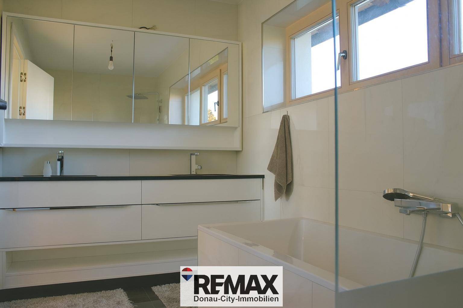 Modernes Badezimmer mit Badewanne, Doppelwaschbecken und großem Spiegelschrank.