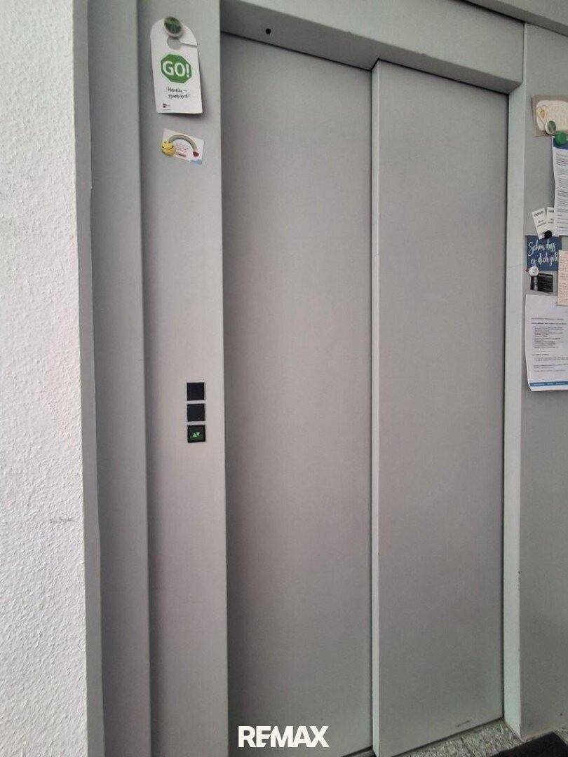 Aufzugstür in einem Gebäude mit einigen Notizen an der Wand.