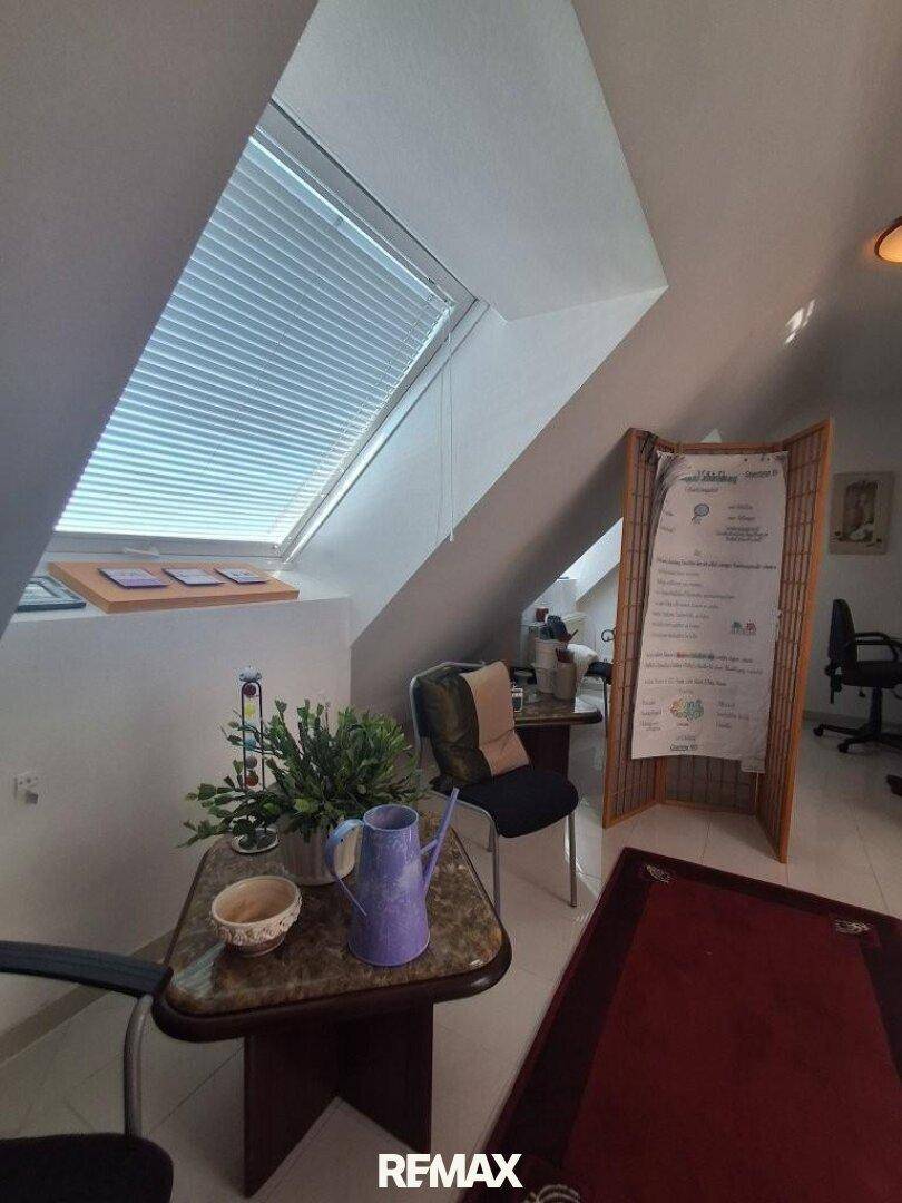 Teil eines Wohnbereichs im Dachgeschoss mit Couchtisch, Pflanzen und einem schrägen Dachfenster.