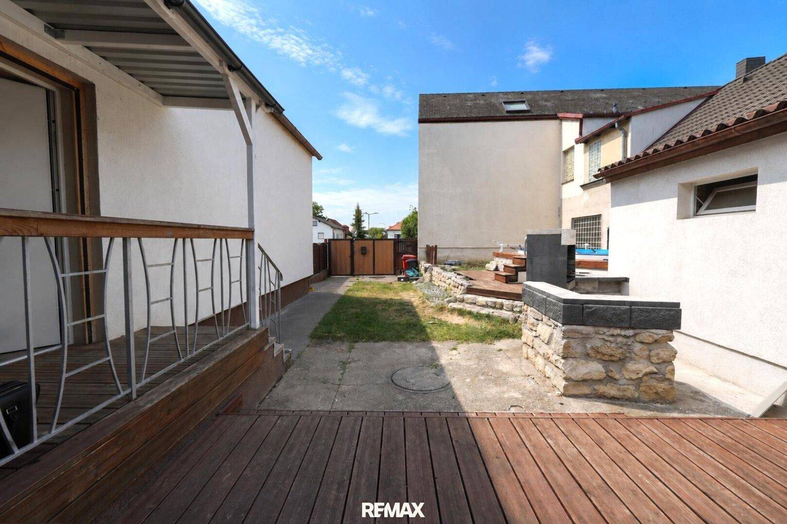 Große Holzterrasse mit Grillbereich und kleinem Garten, ideal für entspannte Stunden im Freien.
