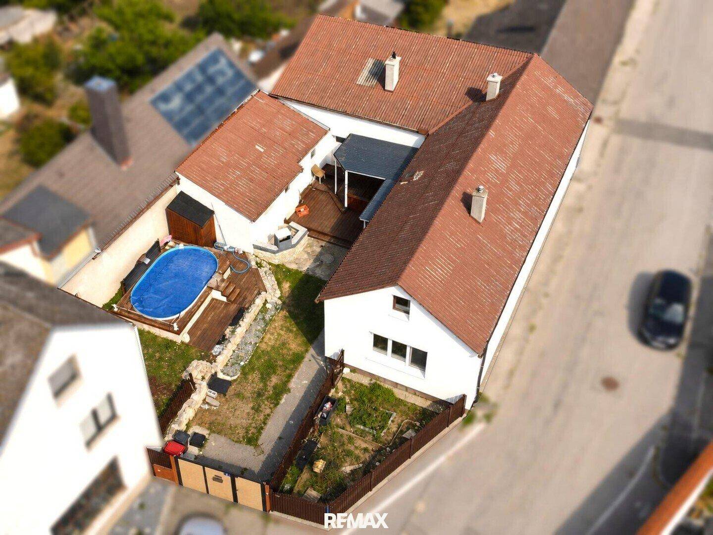 Luftaufnahme des Anwesens mit Haus, Garten, Holzterrasse und einem Aufstellpool.