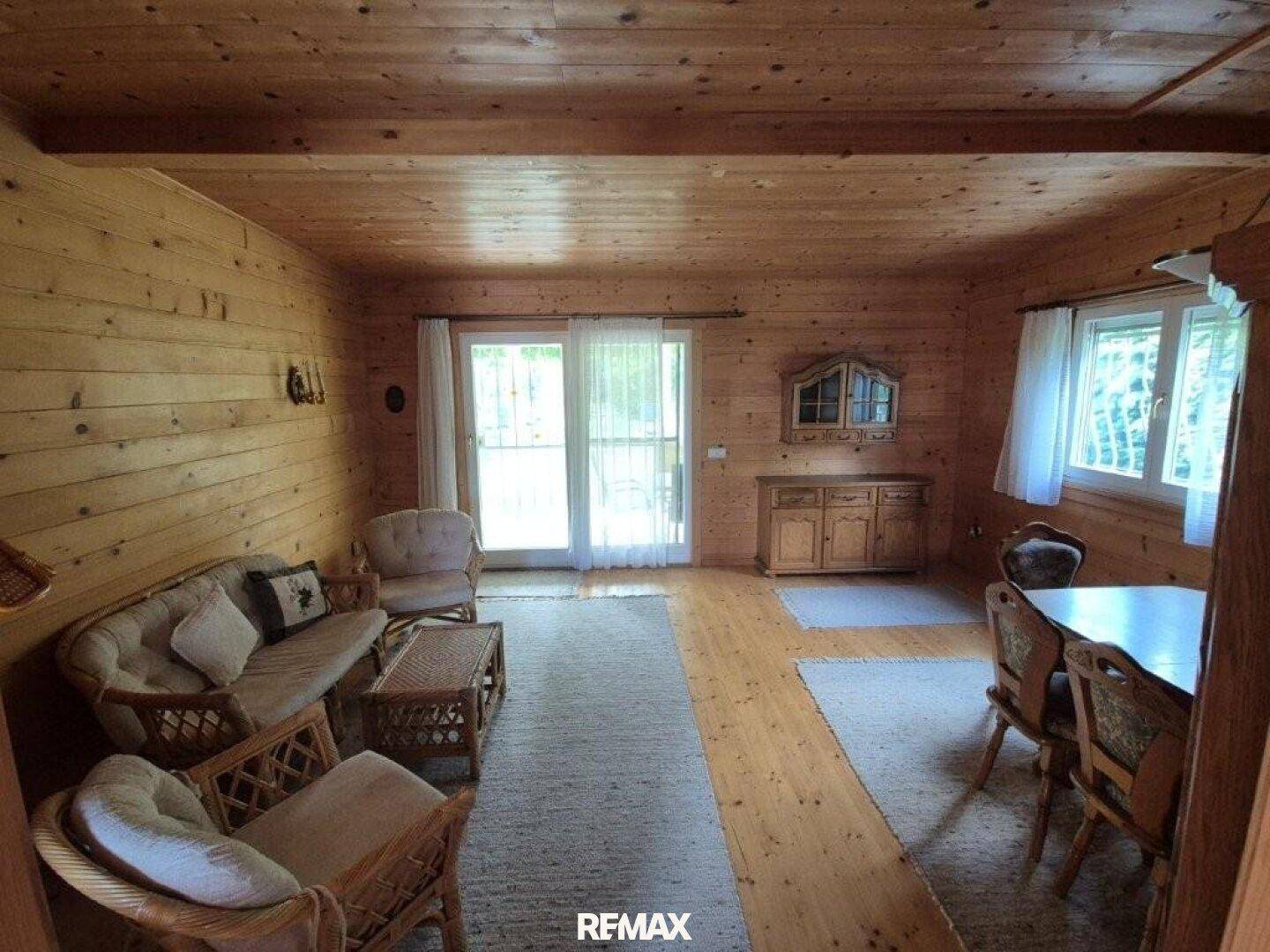 Gemütlicher Wohn-Essbereich mit Holzvertäfelung, Holzboden und Zugang zur Terrasse.
