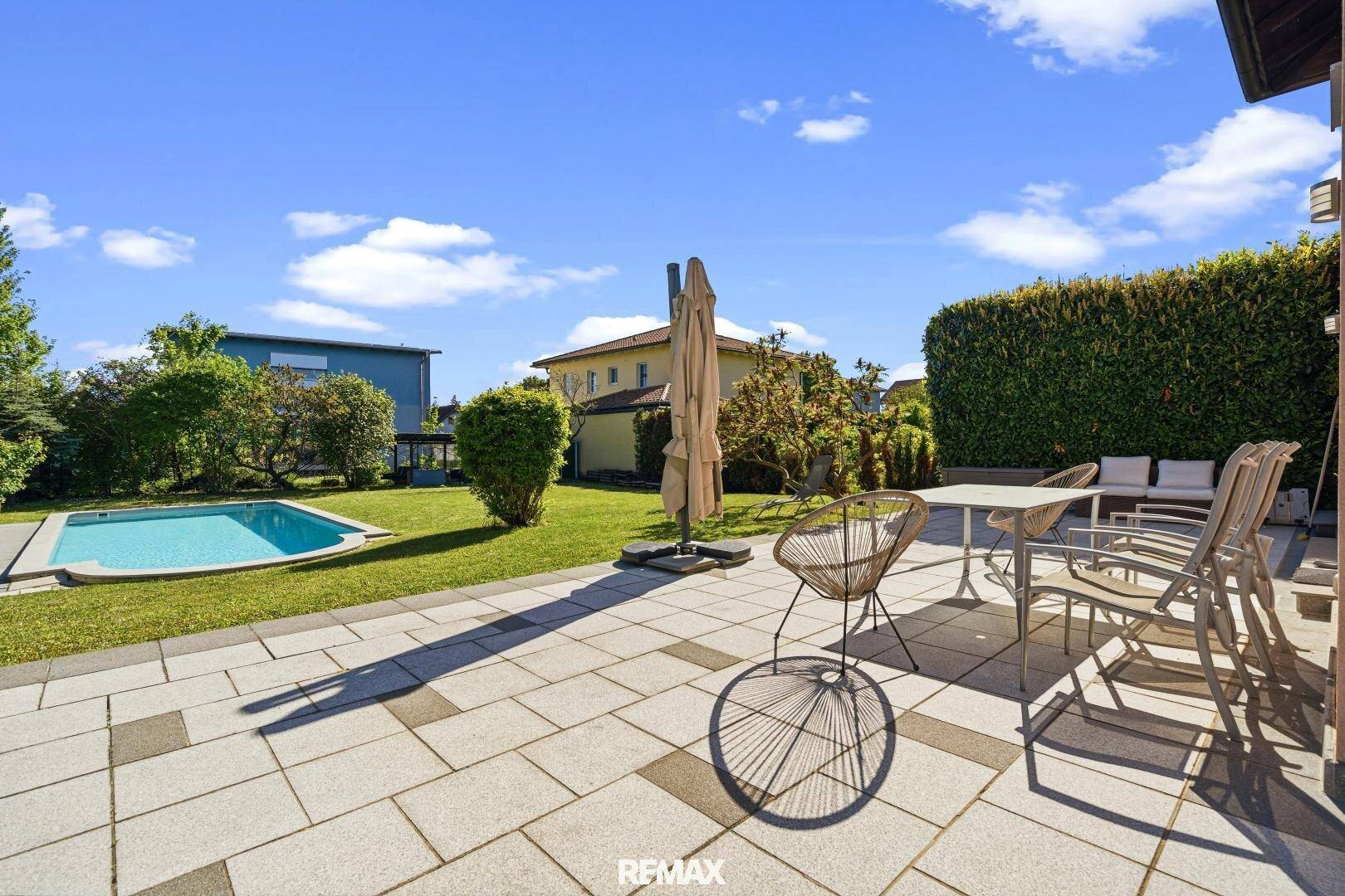 Große gepflasterte Terrasse mit Sitzgelegenheiten und Blick auf den Garten und Pool.