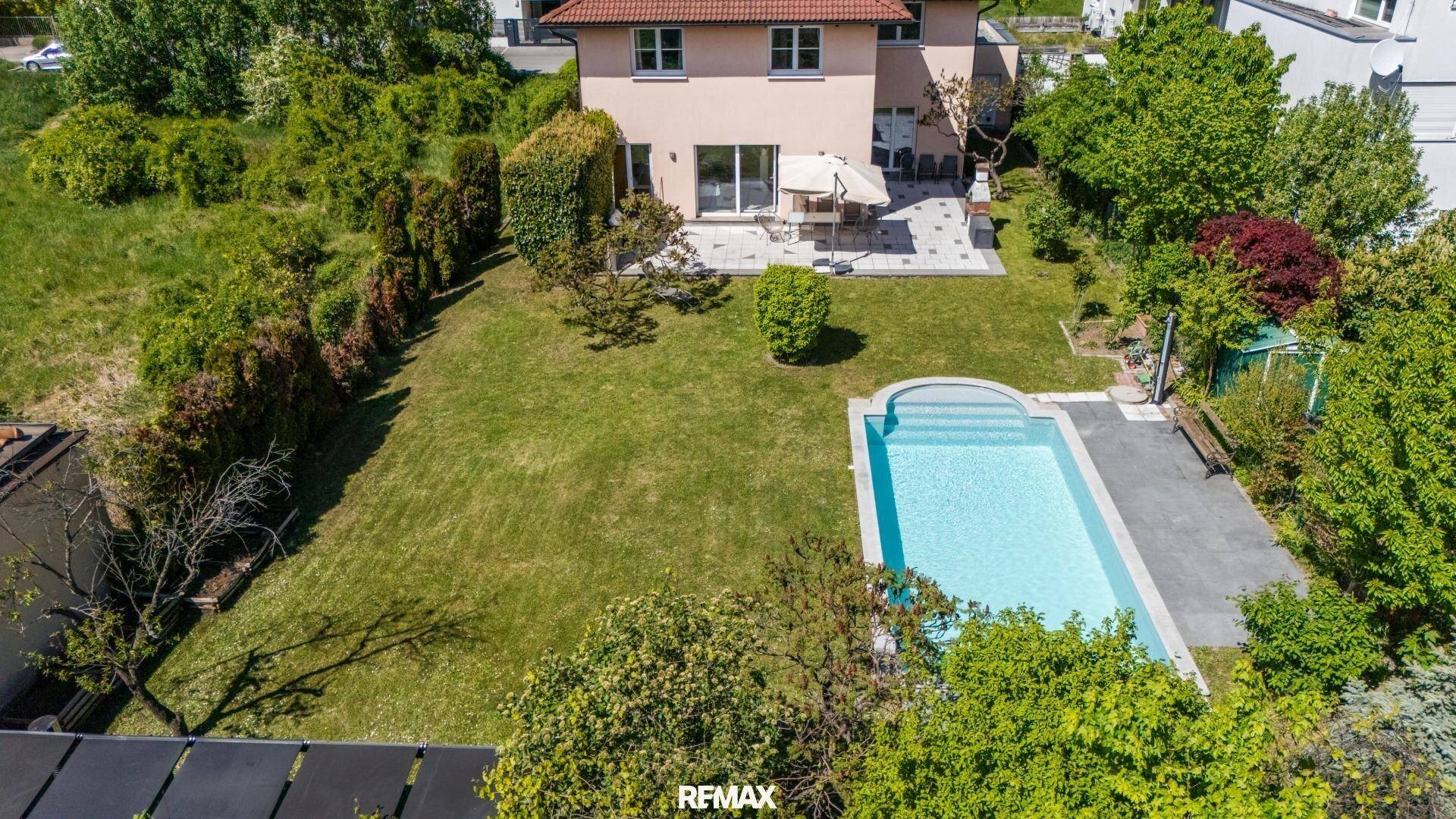 Rückansicht des Hauses mit großer Terrasse, Garten und integriertem Swimmingpool.
