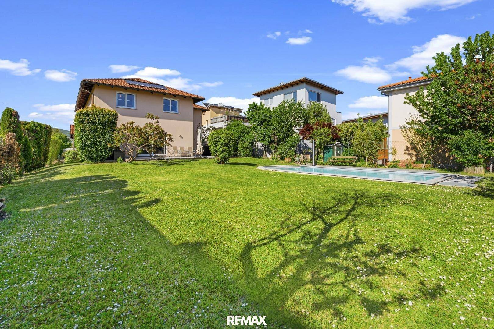 Weitläufiger Gartenbereich mit Rasenfläche, Pool und dem Haus im Hintergrund.