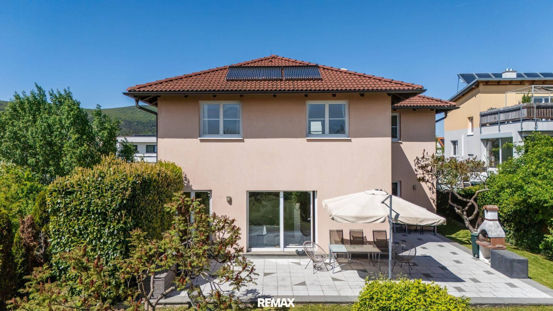 Rückseite des Hauses mit sonniger Terrasse, Gartenmöbeln und Grillbereich.