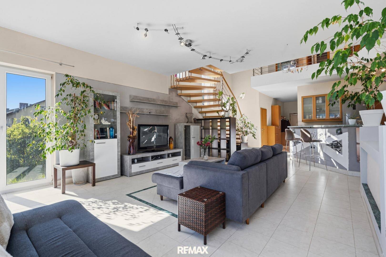 Geräumiges Wohnzimmer mit Treppe, Fliesenboden und Zugang zum Garten.