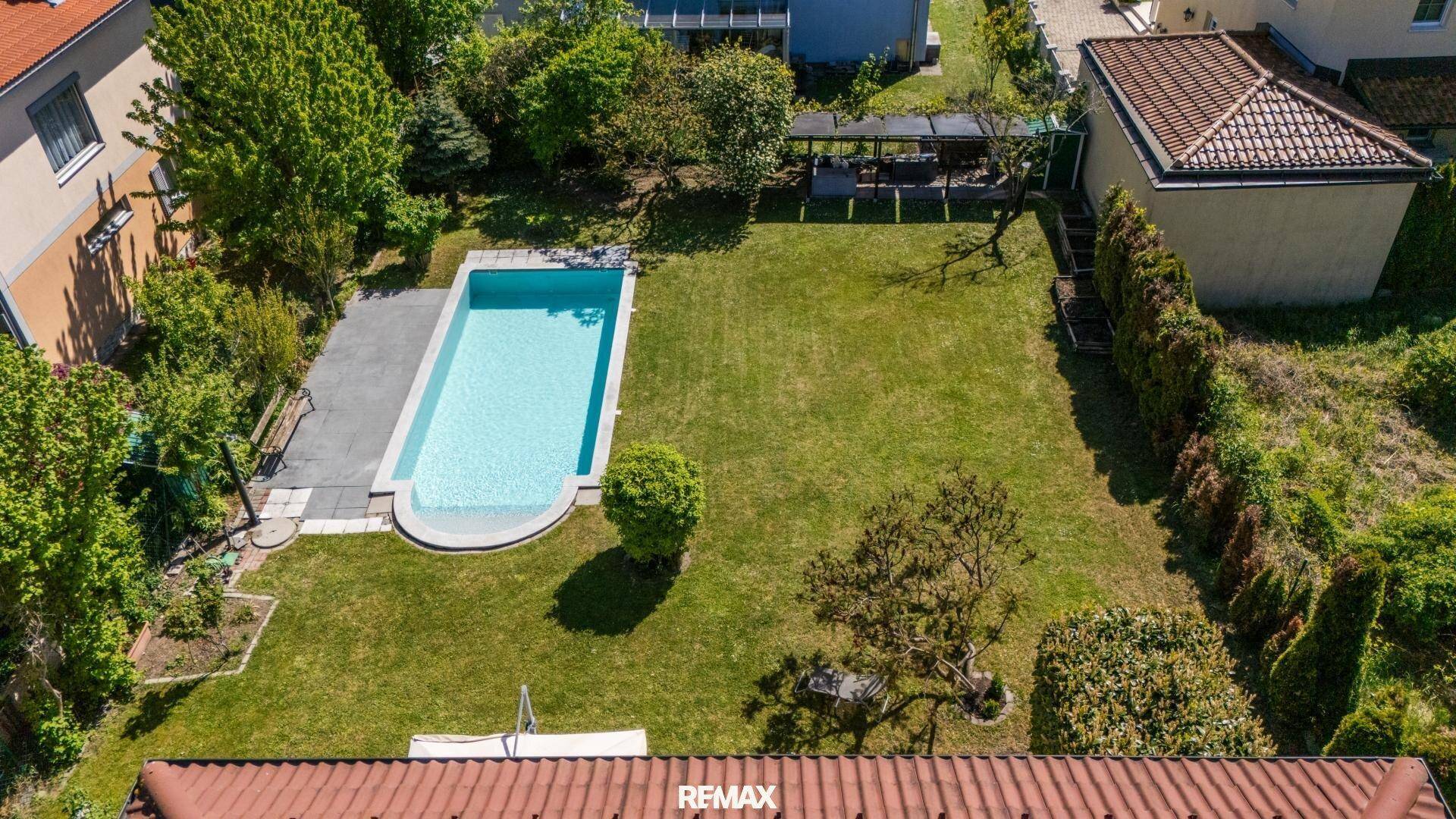 Großer Gartenbereich mit rechteckigem Swimmingpool und weitläufiger Rasenfläche.
