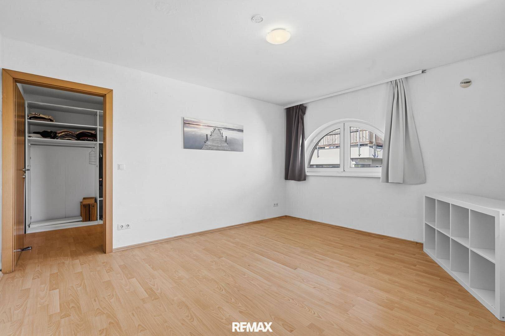 Leeres Schlafzimmer mit Holzboden, weiß gestrichenen Wänden und integriertem Kleiderschrank.