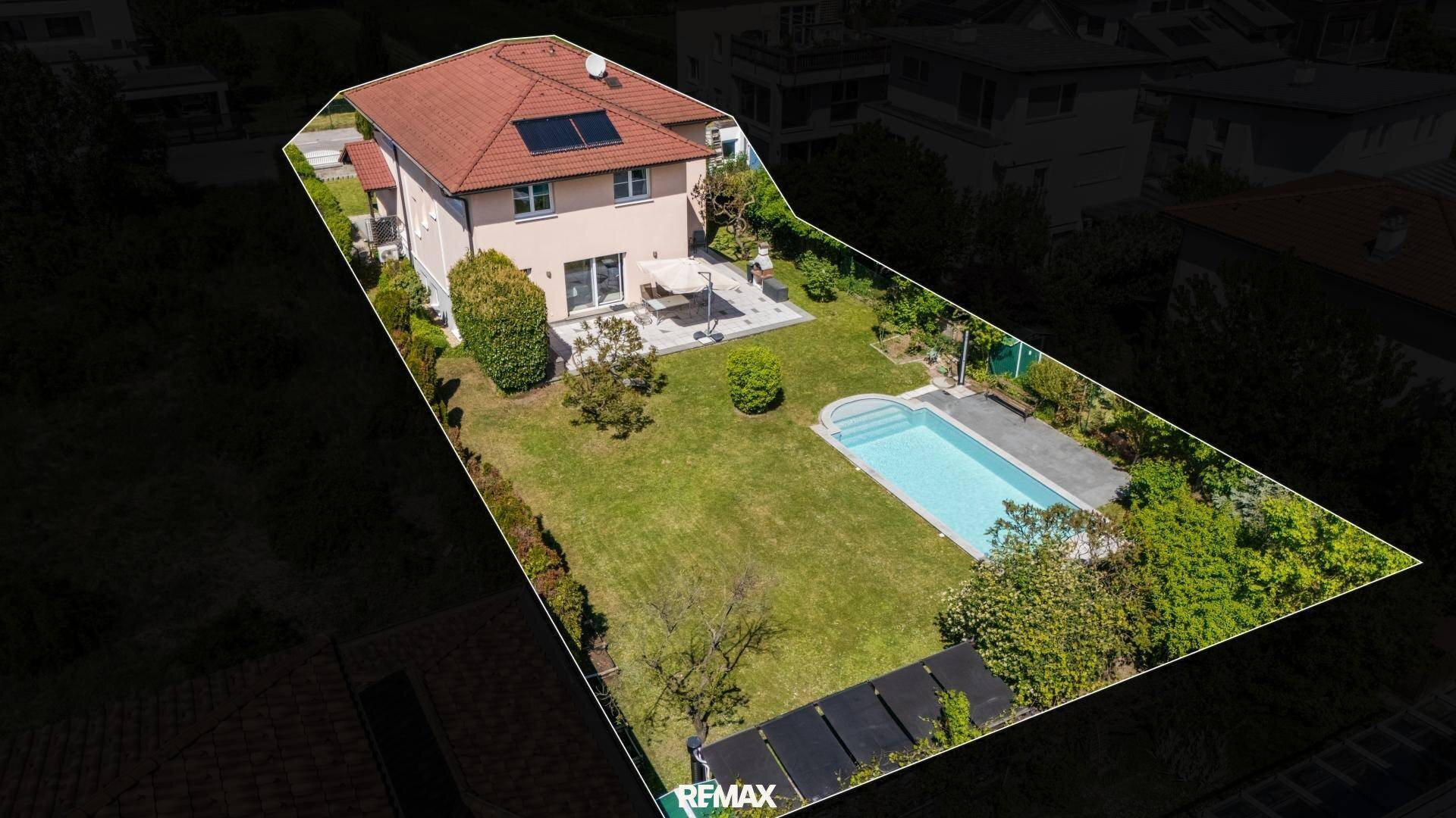 Übersichtliche Luftaufnahme des Grundstücks mit Wohnhaus, Pool und Gartenanlage.