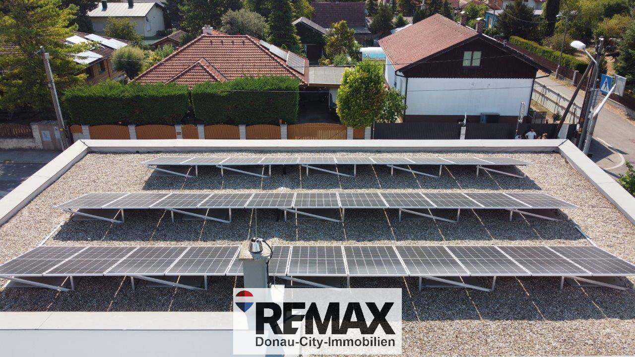Luftaufnahme eines Flachdachs mit zahlreichen Photovoltaikmodulen zur nachhaltigen Energiegewinnung für das Gebäude.