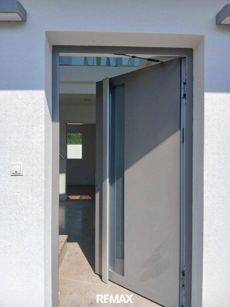 Moderne Eingangstür, die einen hellen und einladenden Flur im Inneren des Hauses offenbart.