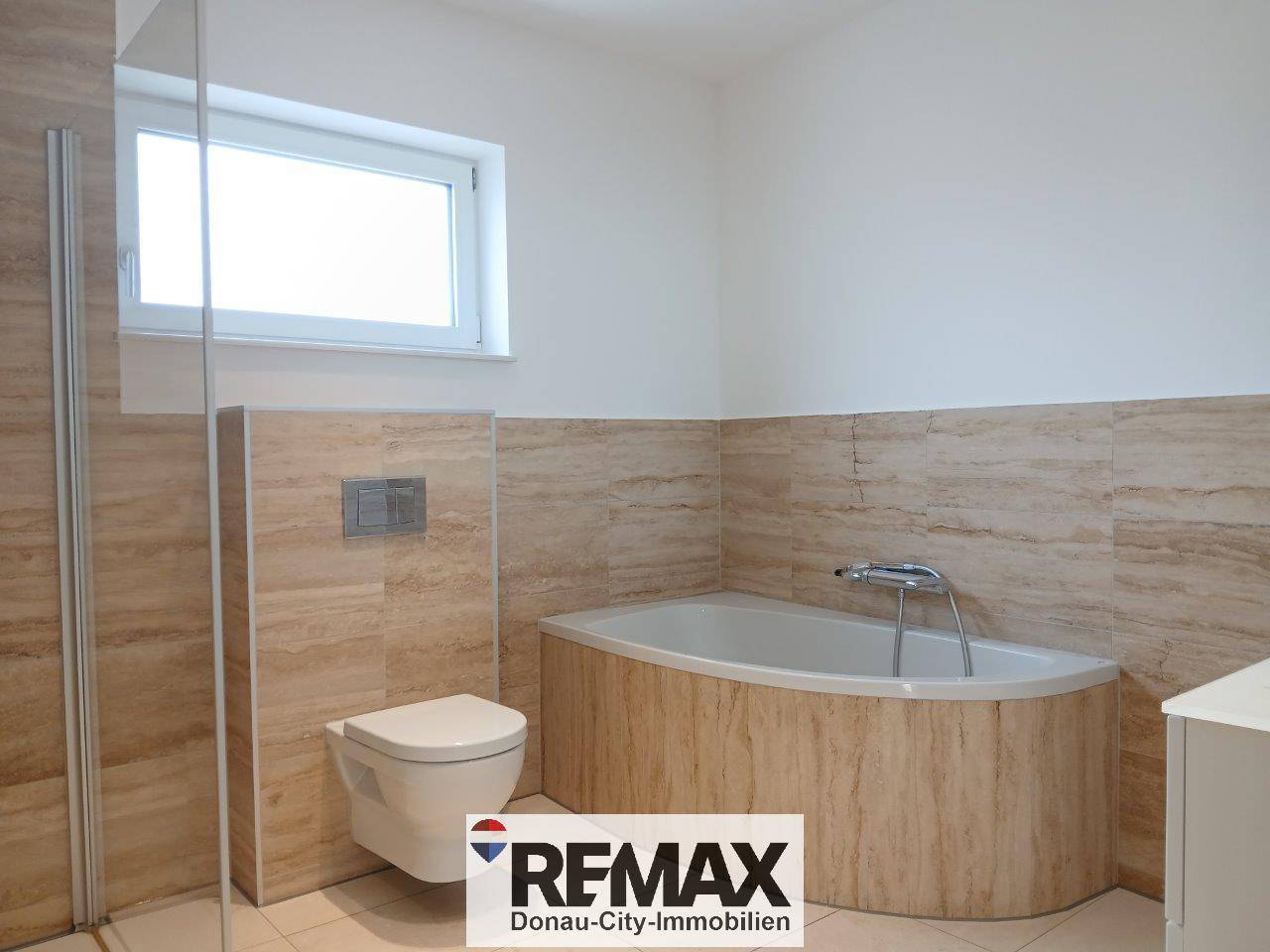Modernes Badezimmer mit wandhängendem WC und Eckbadewanne, umgeben von hellen Fliesen.