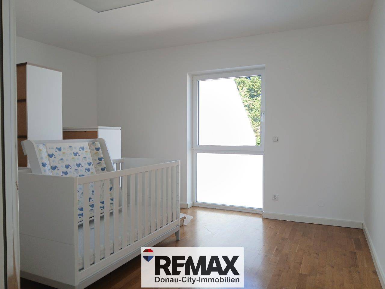 Helles Kinderzimmer mit Holzboden und einem Babybett, das viel Tageslicht erhält.