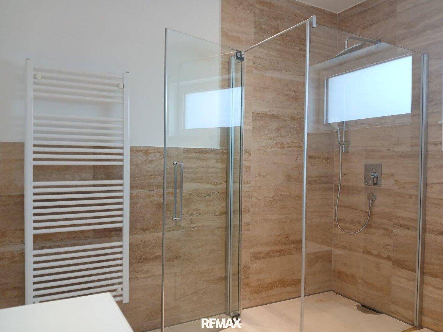 Modernes Badezimmer mit Glasduschkabine und beheiztem Handtuchhalter.