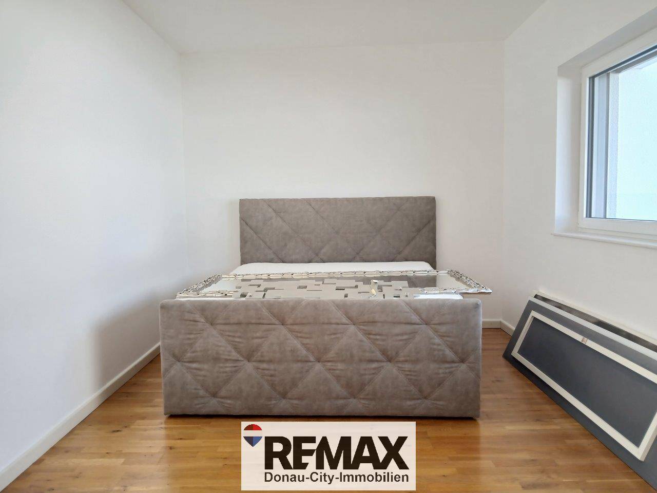 Schlafzimmer mit Holzboden und einem gepolsterten Bettrahmen, bereit zur Einrichtung.