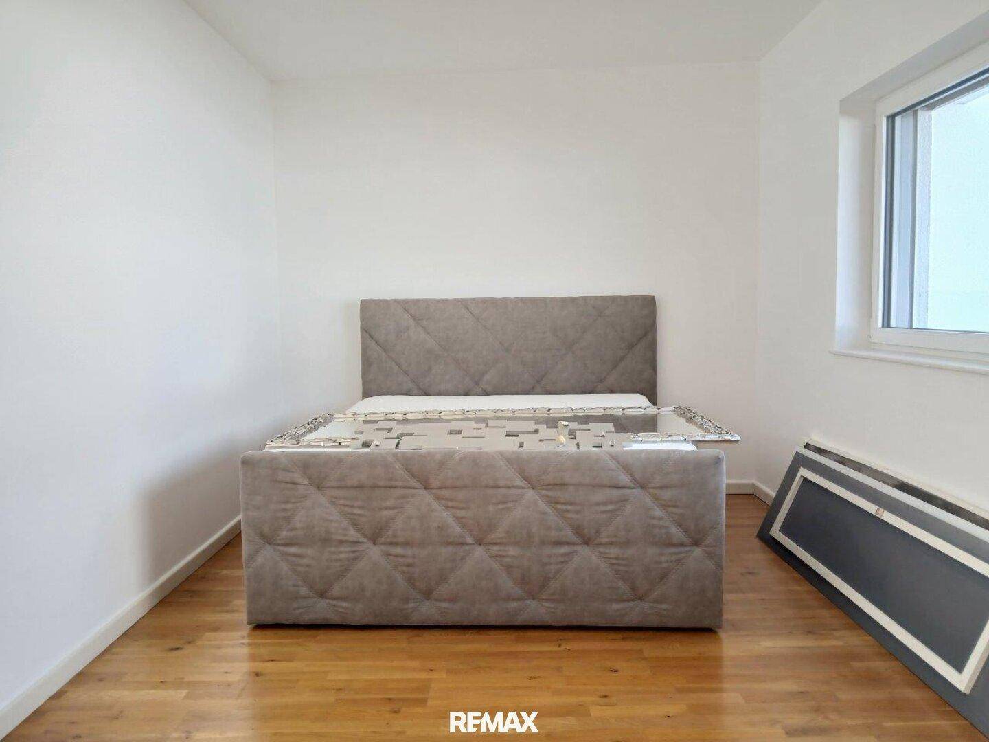 Schlafzimmer mit Hartholzboden und einem modernen Bettgestell.